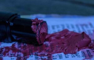 un tube de rouge à lèvre écrasé sur un texte imprimé