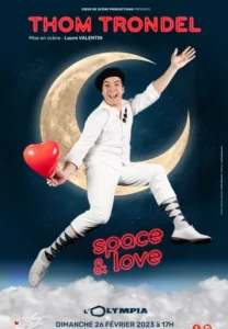 Thom trondel assis sur un croissant de lune, un coeur à la main, en costume blanc. Affiche Thom trondel dans "Love & Space"