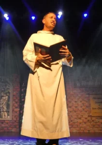 Un homme en habit religieux tient un grand livre