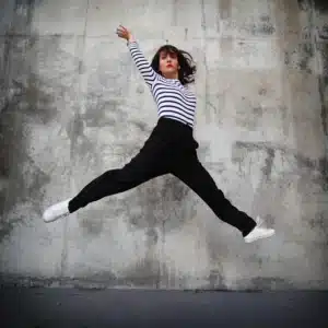 portrait d'Olivia Moore saute en l'air devant un mur bétonné