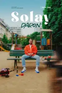 Affiche de Daron avec Solay. Solay assis sur un banc dans un jardin d'enfant . Baskets, jean et veste rouge