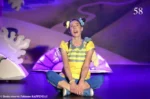 Les vacances de Capucine, photo de scène de Stéphanie Pierron à genoux devant un décor violet