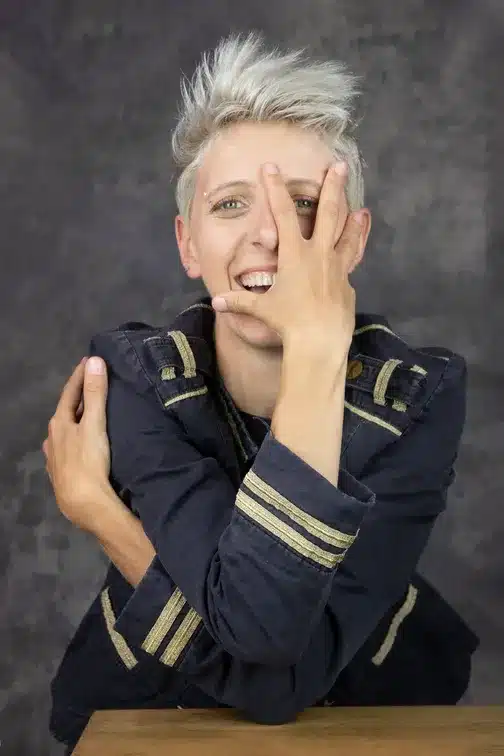 Charlotte Boisselier. Portrait photo, en veste de musicien de fanfare, bras croisés, la main droite devant le visage