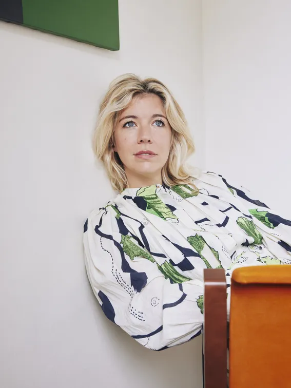 Mélodie Fontaine assise sur une chaise en équilibre , pensive.