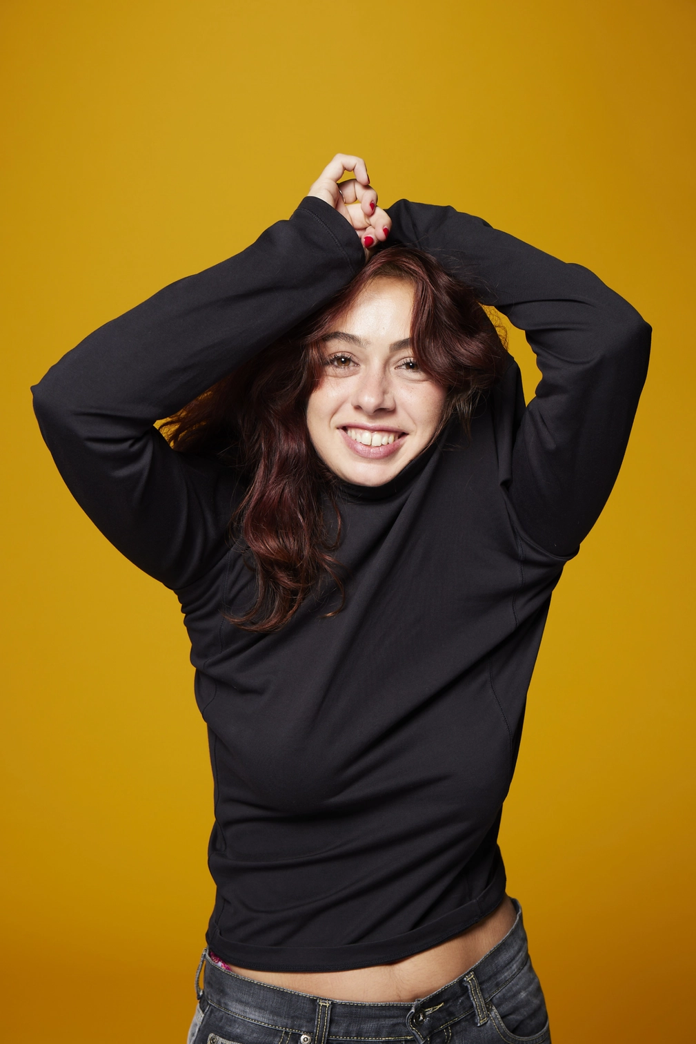 Emma Bojan en pull noir et jean les mains au dessus de la tête