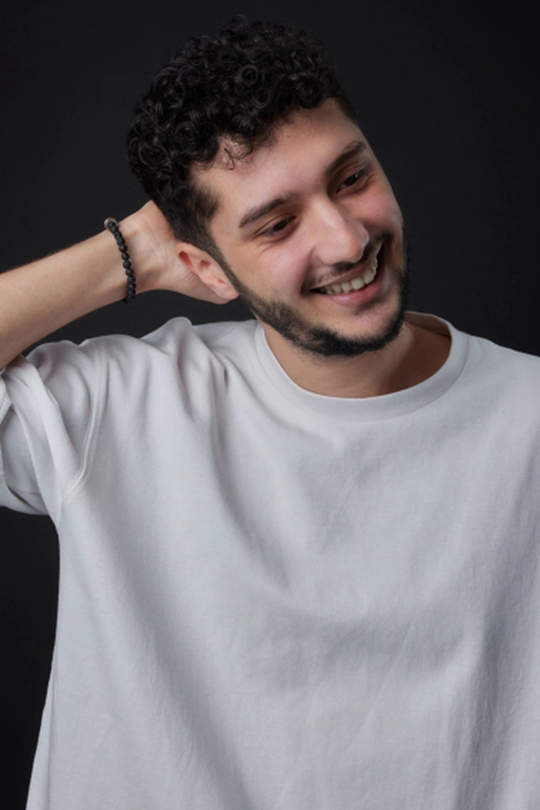 Portrait d'Elies Zoghlami souriant, chemise blanche une main derrière la tête