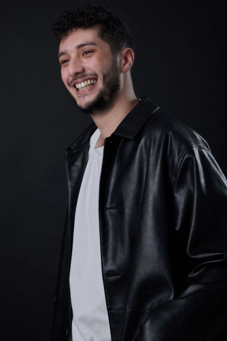 Portrait d'Elies Zoghlami souriant en blouson noir, en regard public