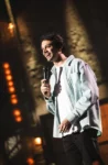 Photo de Alexis Tramoni sur scène micro à la main et souriant