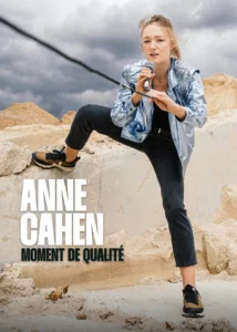 Affiche de Anne Cahen dans Moment de Qualité. Un micro à la main debout sur des pierres, elle tire sur le fil du micro.