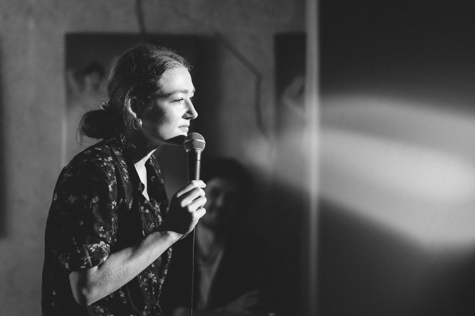 Anne Cahen en spectacle; de profil en noir et blanc, un micro à la main