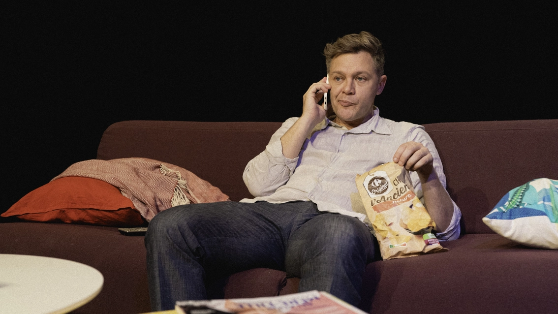 au téléphone un paquet de chips près de lui