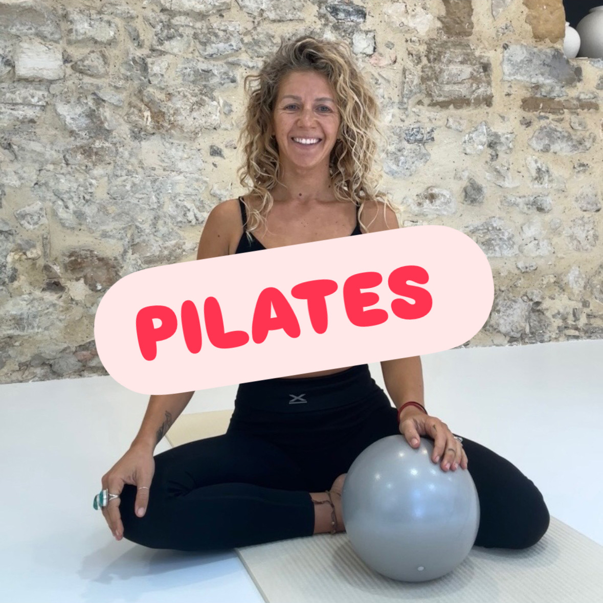Portrait de Camille Fouquet professeure de Pilates, à genoux sur un tapis avec unballon d'exercice entre les jambes