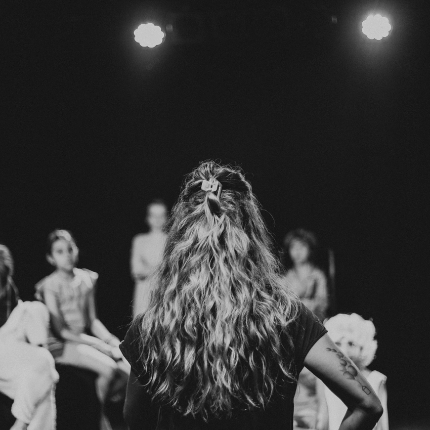 Photo d'un cours de théâtre avec Camille Hugues de dos, et des enfants partout en face d'elle