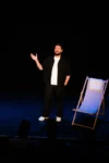 Robin Gomez debout sur scène, un transat blanc à ses pirds