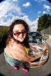 Photo dans la nature de Marie Brauer entrain de laver le capot de sa voiture en maillot de bain