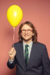 Photo de Antek, décontracté, en costard cravate, un ballon jaune à la main.