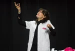 Photo de Gigi sur scène, en blouse blanche et en pleine démonstration
