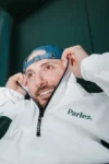 Photo d'Antoine Magyar, souriant, il a relevé le col de sonb sweat jusqu'aux oreilles
